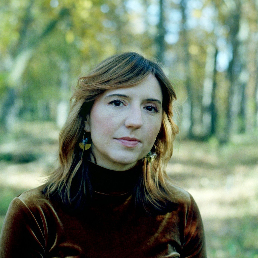 headshot of Dr. Sarah Minor, a wood in the backgroun