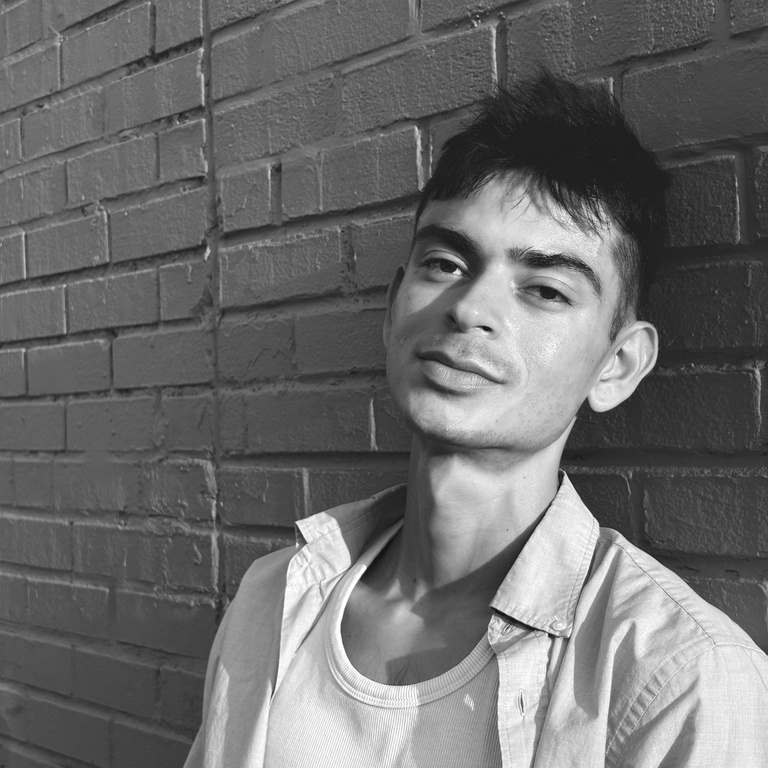 black and white photo of Erick Aguilar leaning on a brick wall
