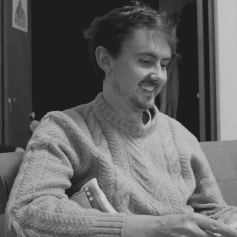 black and white photo of Matthew Byrne smiling in a sweater